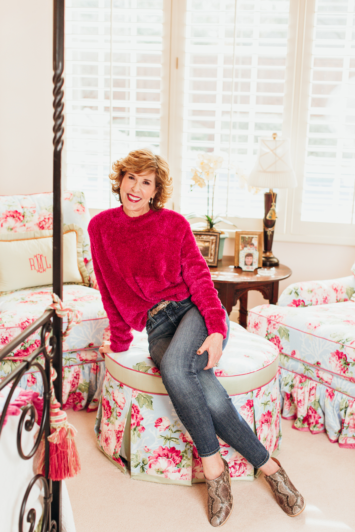 woman in pink fuzzy sweater and jeans posing in her bedroom