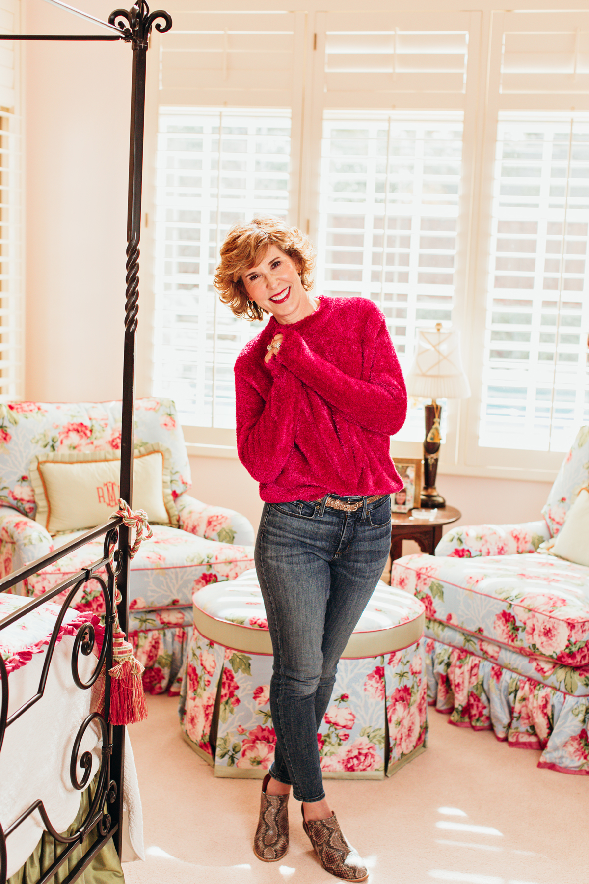 woman in pink fuzzy sweater and jeans posing in her bedroom