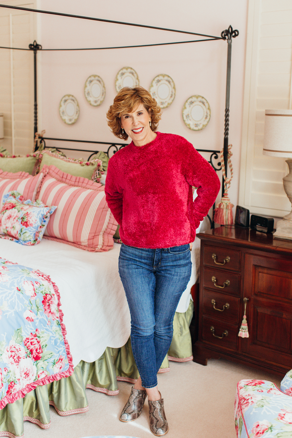 woman in pink fuzzy sweater and jeans posing in her bedroom