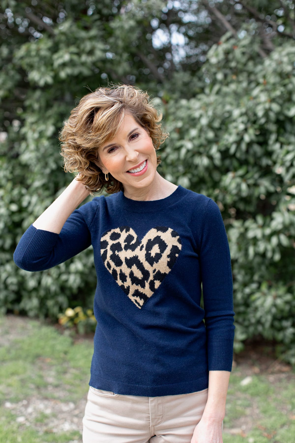 woman in heart sweater with hand in hair