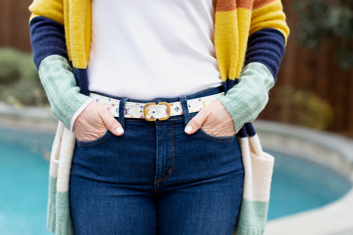 womans wearing designer belt with hands in jean pockets