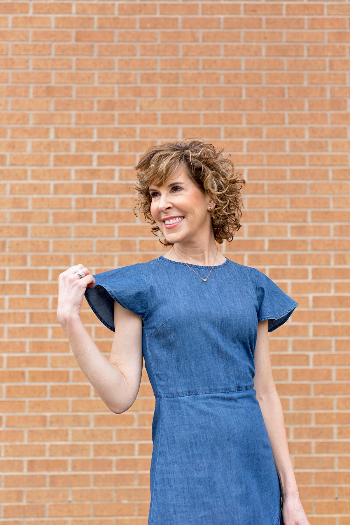 waist up of woman holding her sleeve and looking to the side