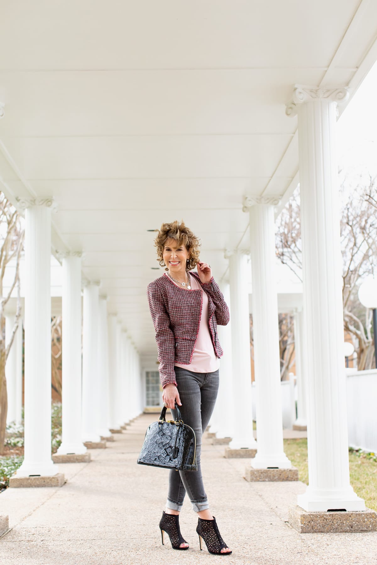 woman in black and pink outfit standing outside among white columns