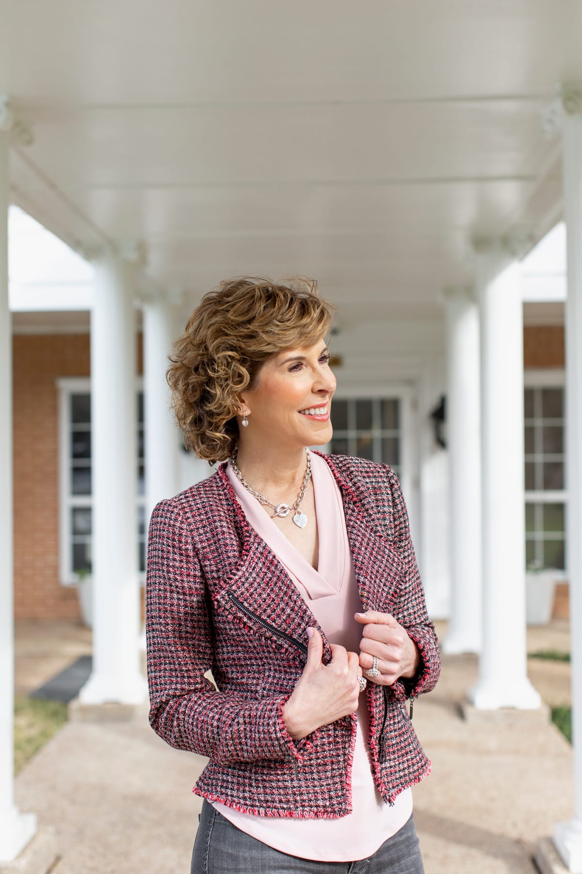 woman in black and pink outfit standing outside among white columns