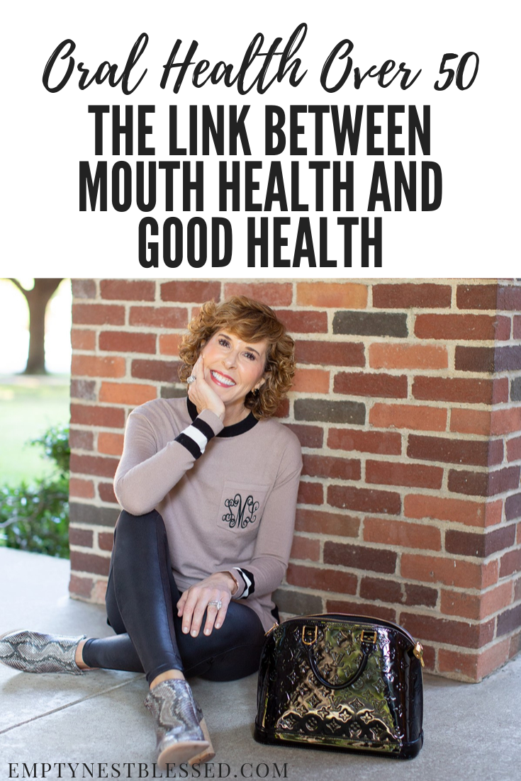 woman in tan monogrammed sweater sitting in front of a brick wall with text above