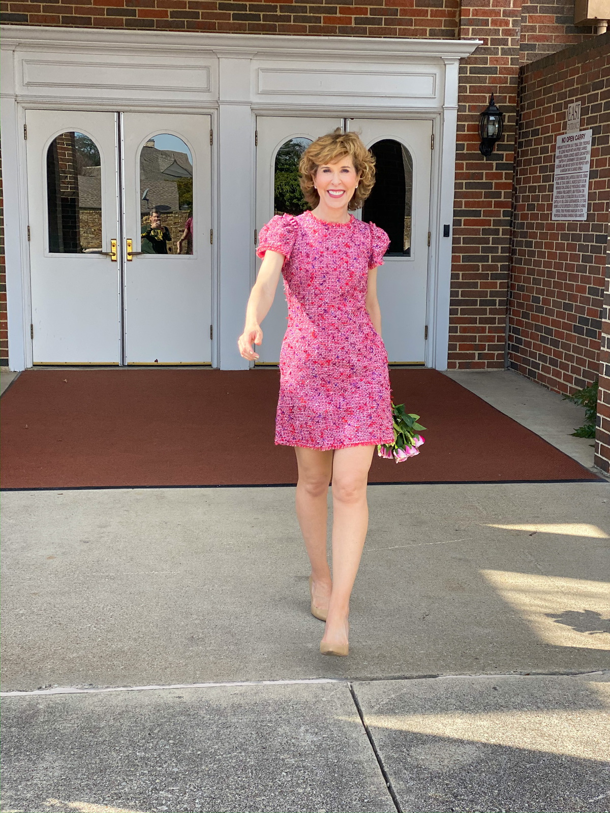 woman in pink tweed dress holding pink roses