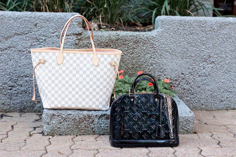 two designer handbags sitting on the ground