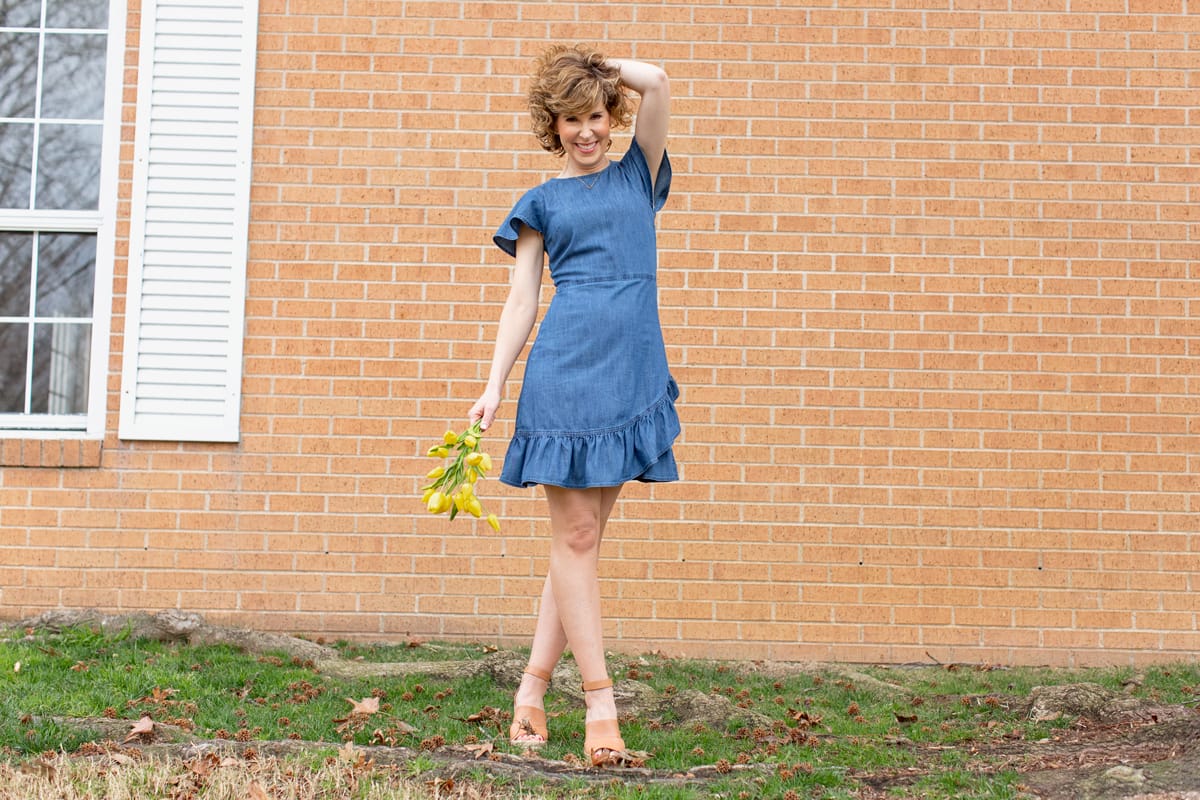 woman in blue dress holding her hair and yellow flowers