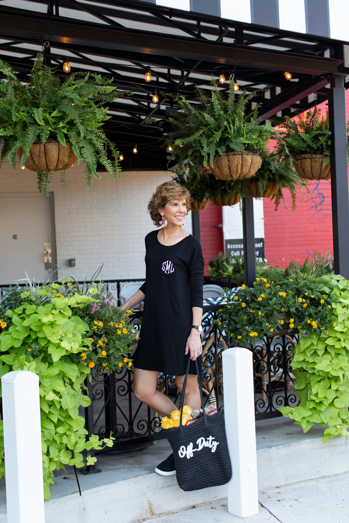 woman wearing black dress standing in front of an outdoor restaurant patio