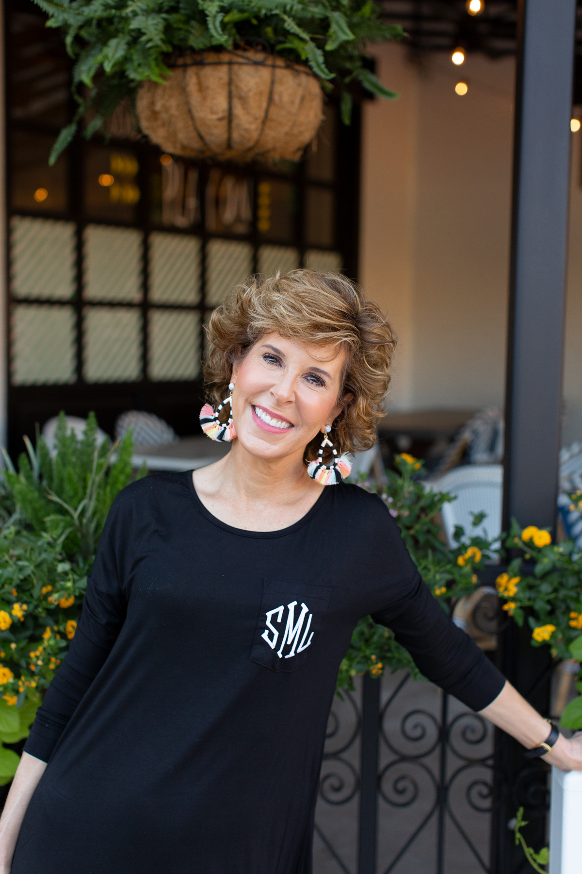 woman in black dress with colorful earrings