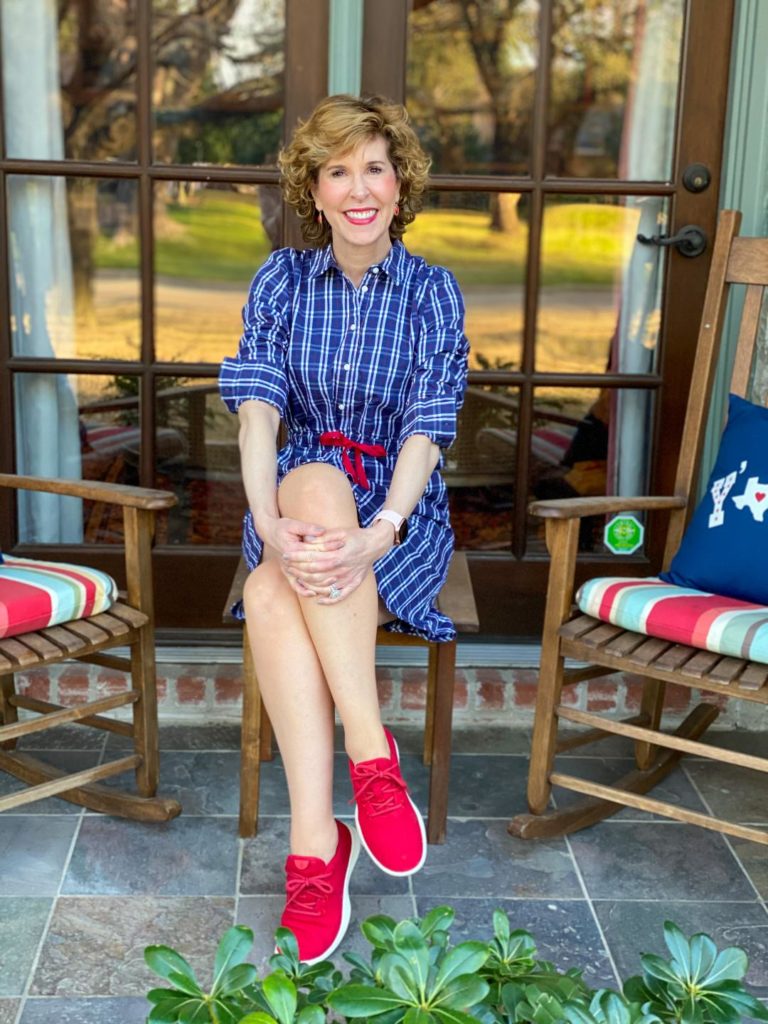 woman in blue dress with red shoes sitting on her front porch