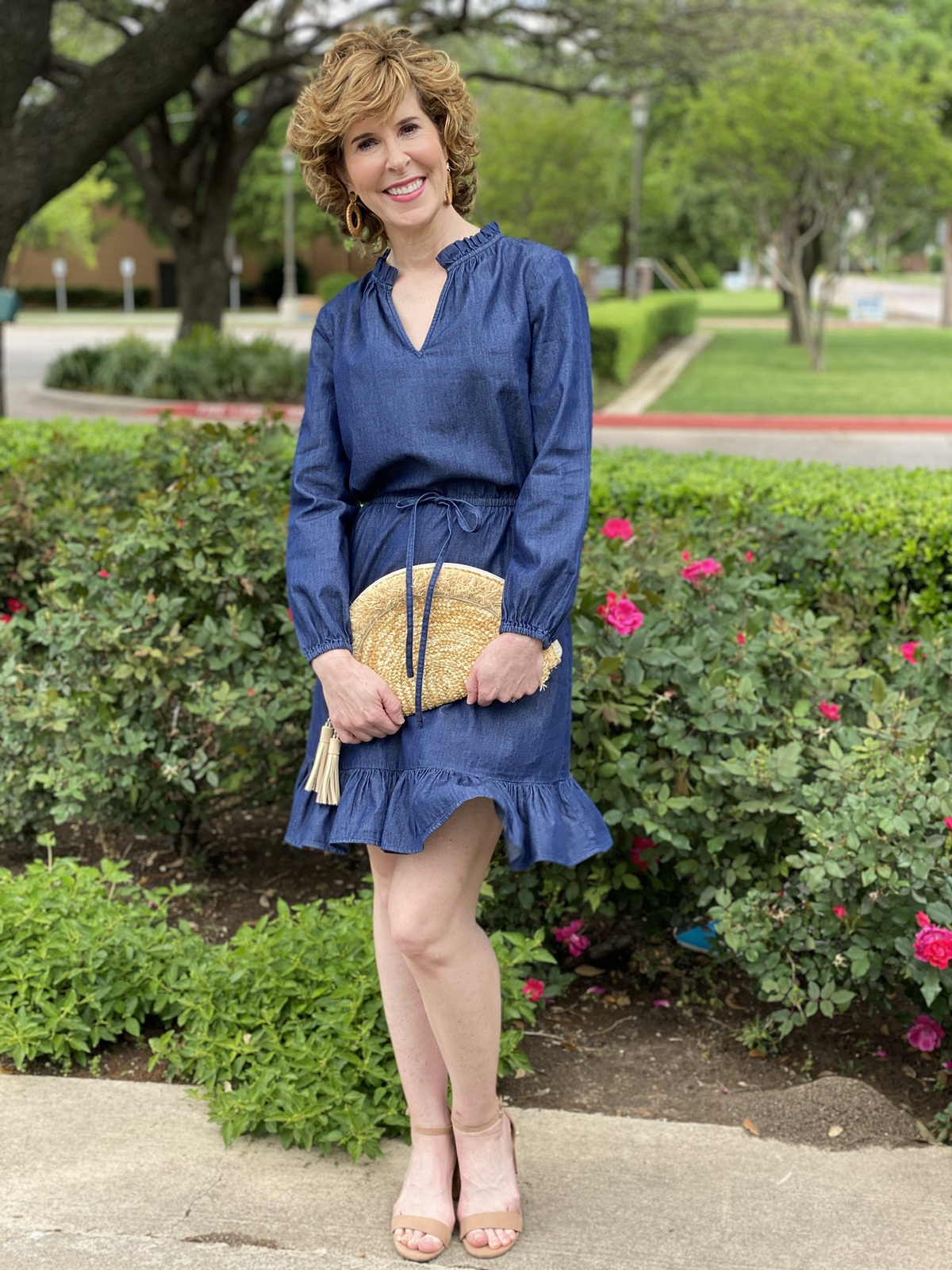 woman wearing chambray draper james popover dress and holding fan clutch straw bag