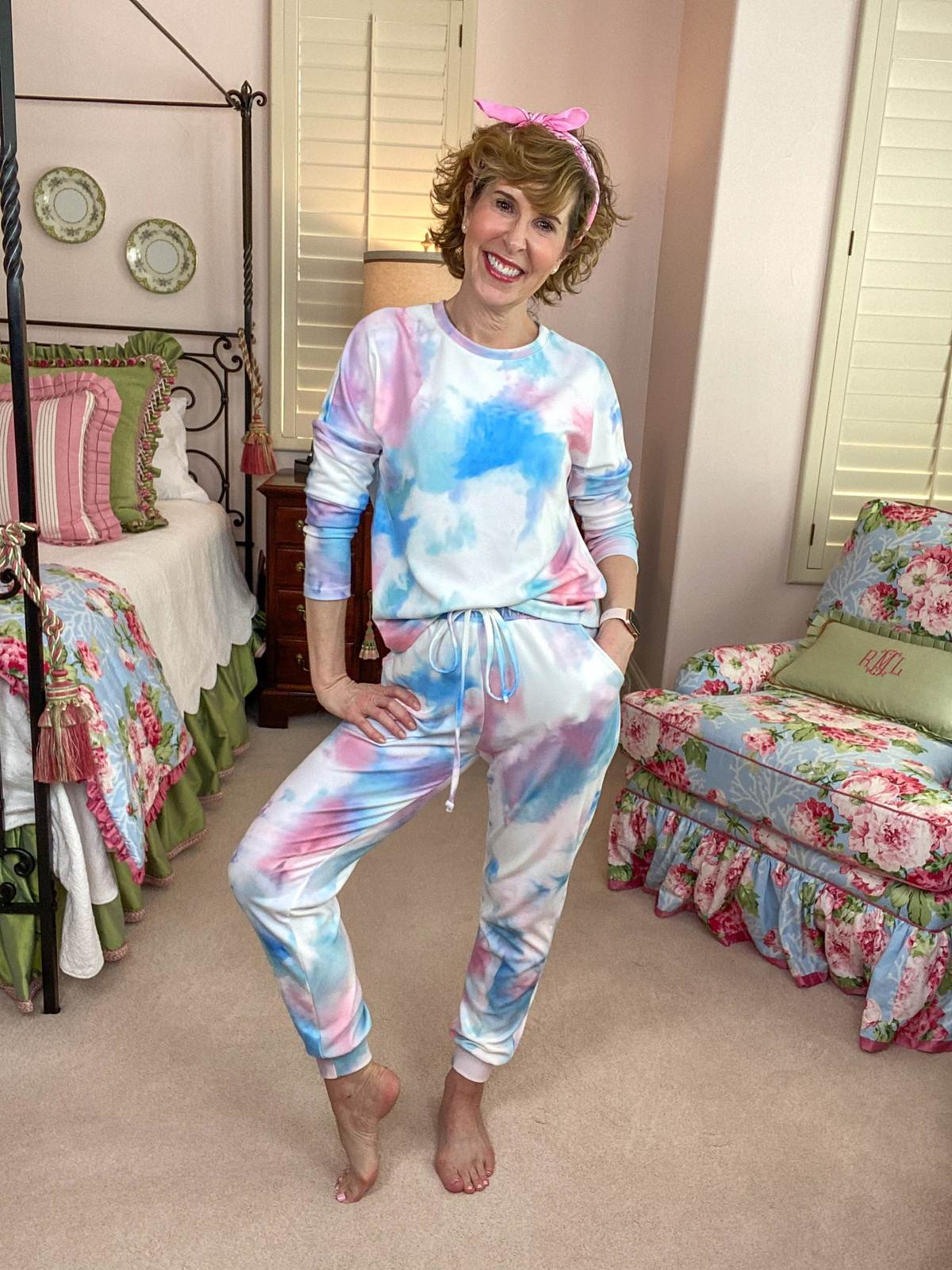 woman wearing tie dye loungewear standing in a bedroom