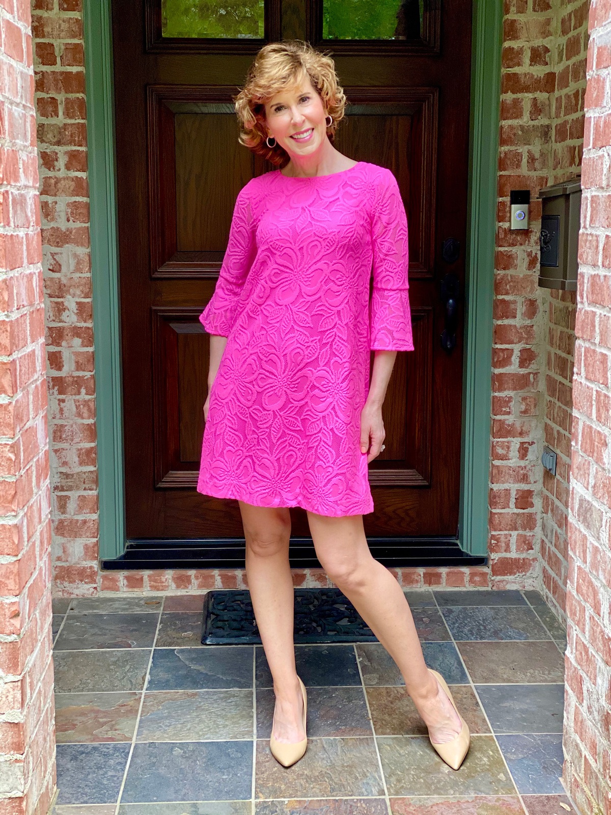 woman wearing neon pink dress standing on front porch