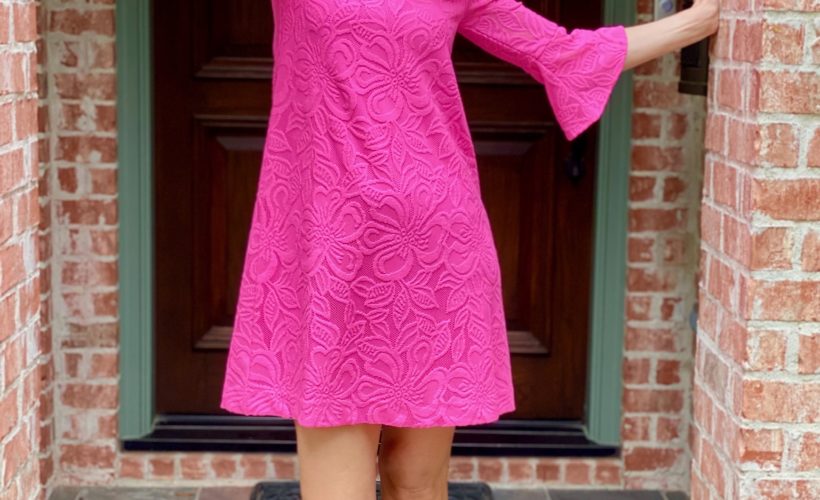 woman wearing neon pink dress standing on front porch