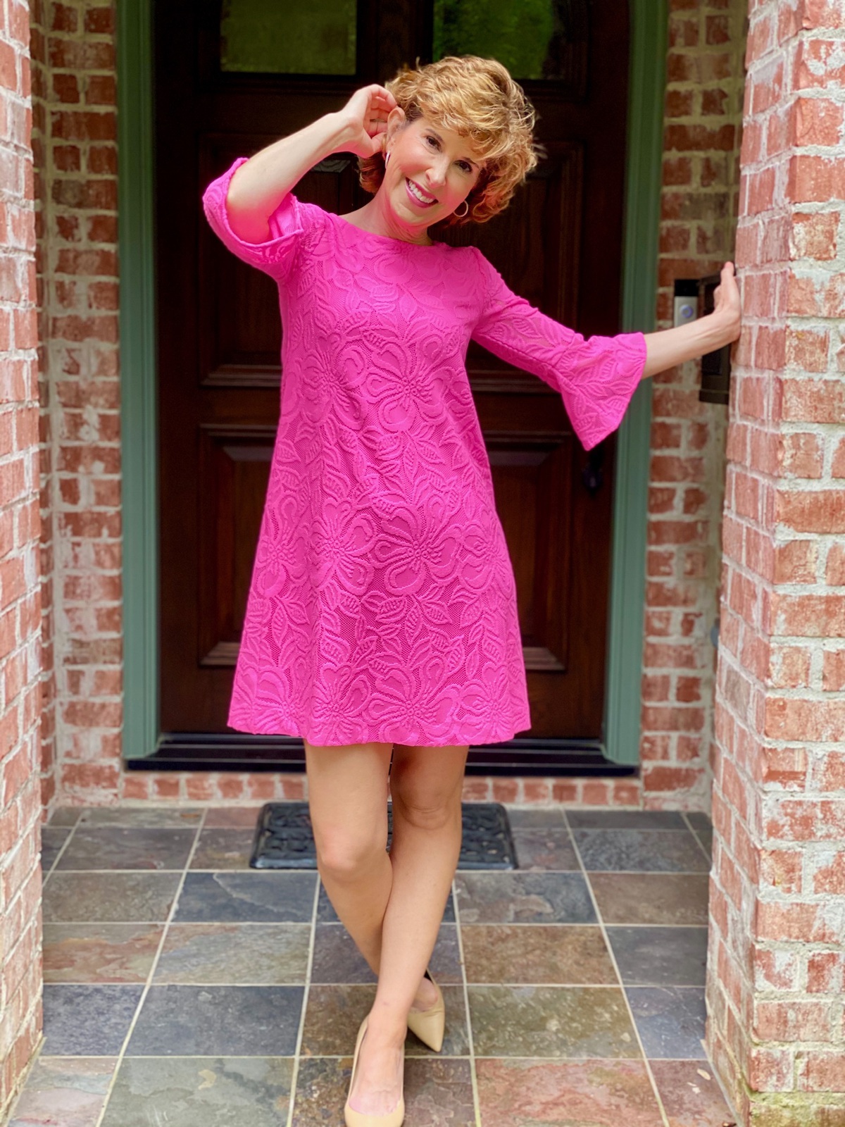 woman wearing neon pink dress standing on front porch