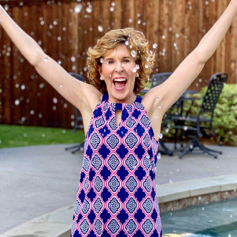 woman in blue and pink dress standing in a pool throwing water in the air