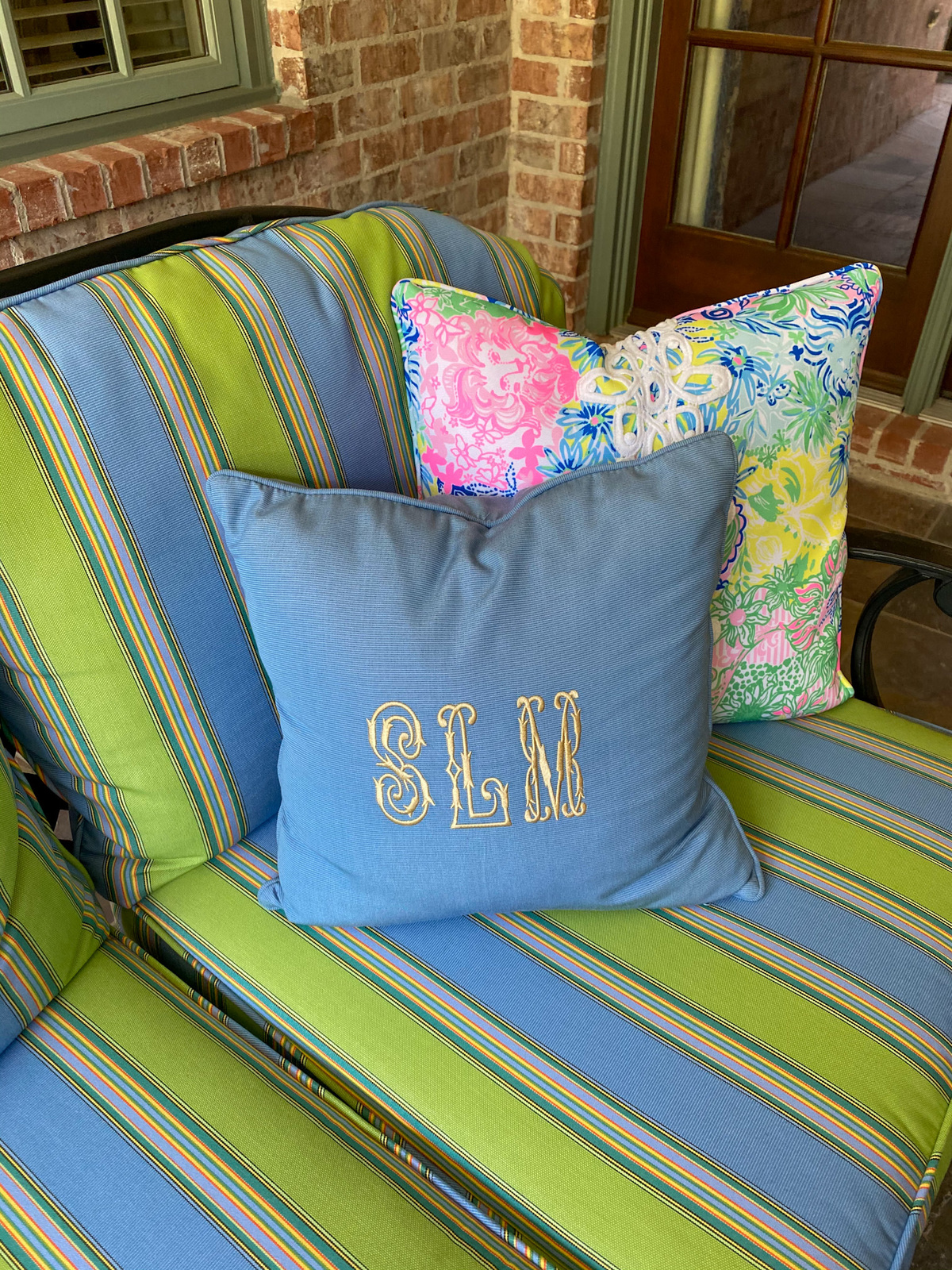 frontgate blue monogrammed square pillow sitting on striped cushion patio furniture
