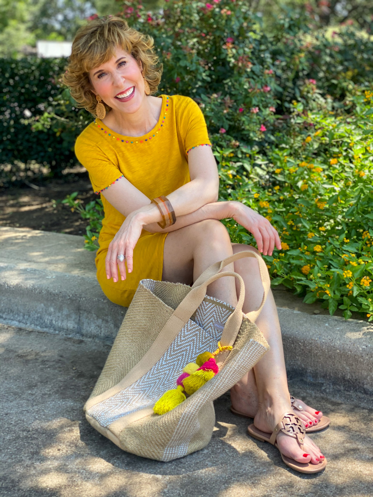 woman in gold boden charlie jersey dress sitting on a curb with a jute bag