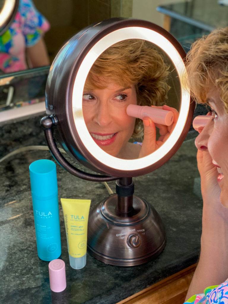 woman applying clean beauty product from pink tube to undereye area