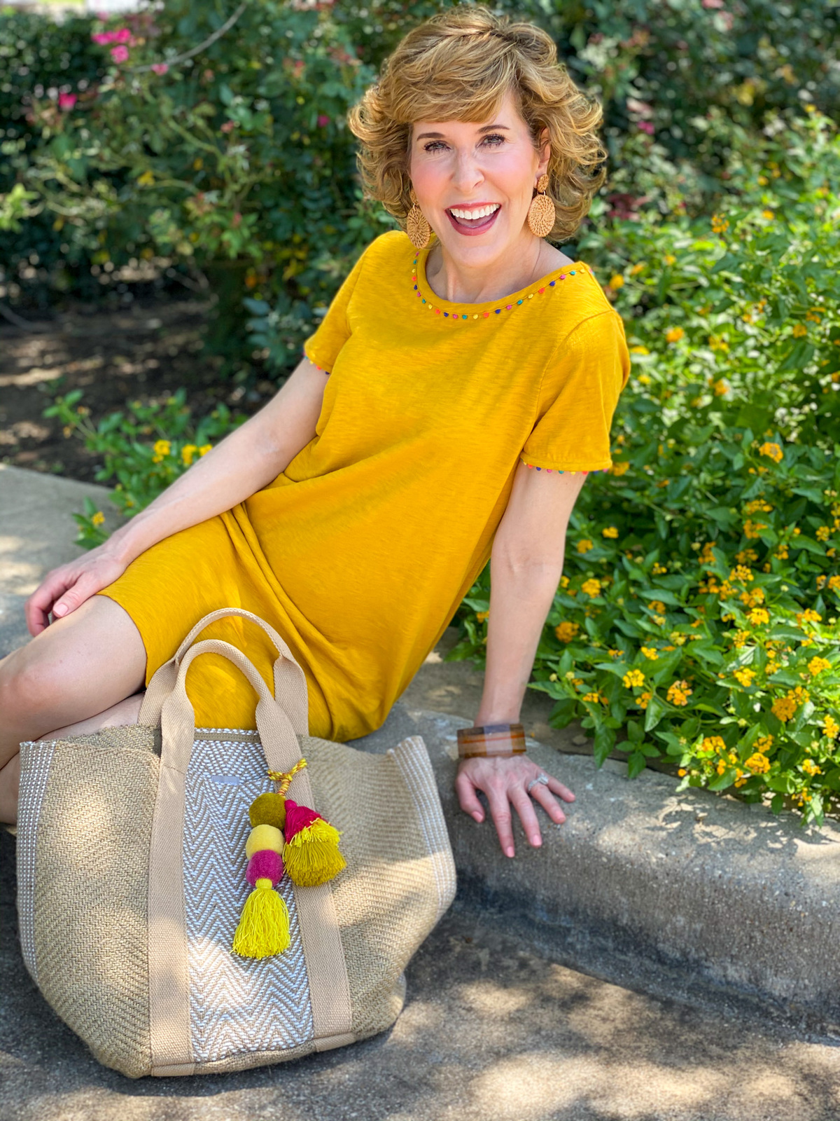 woman wearing boden gold charlie jersey dress sitting on curb by chico's jute tote