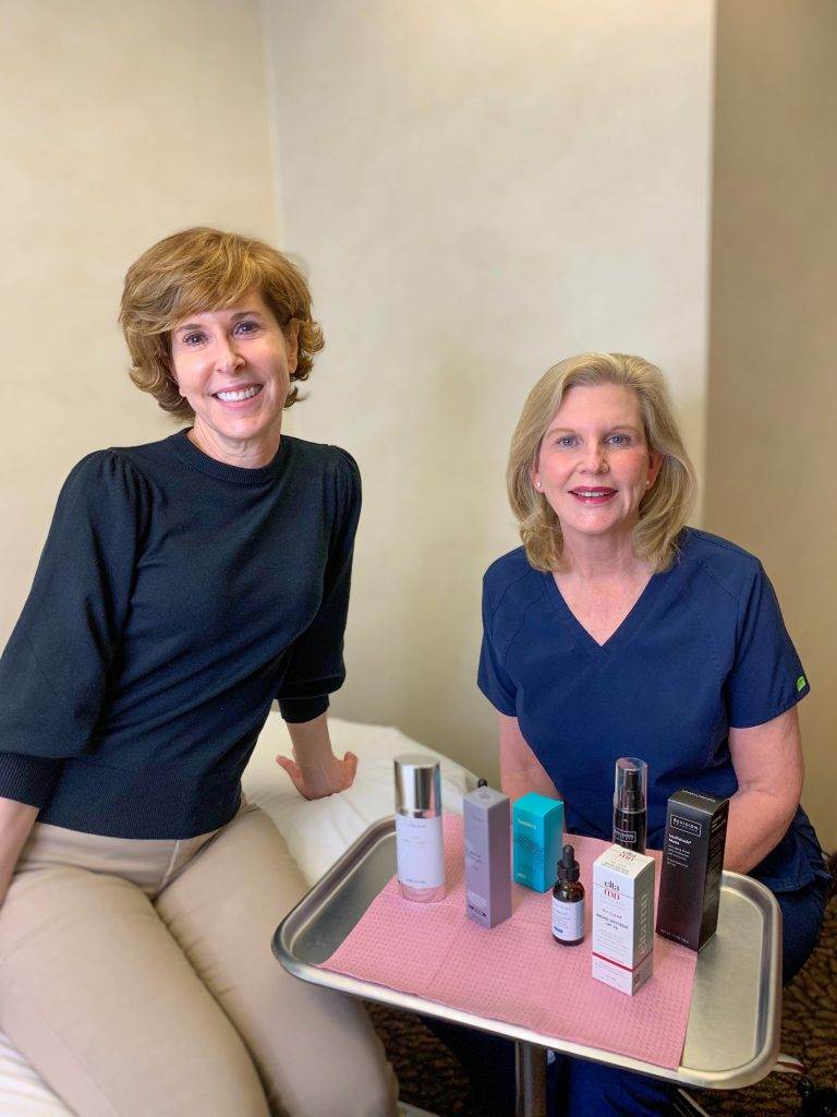 woman sitting with dermatologist dr lori stetler in front of a tray of the best skincare products for women over 50