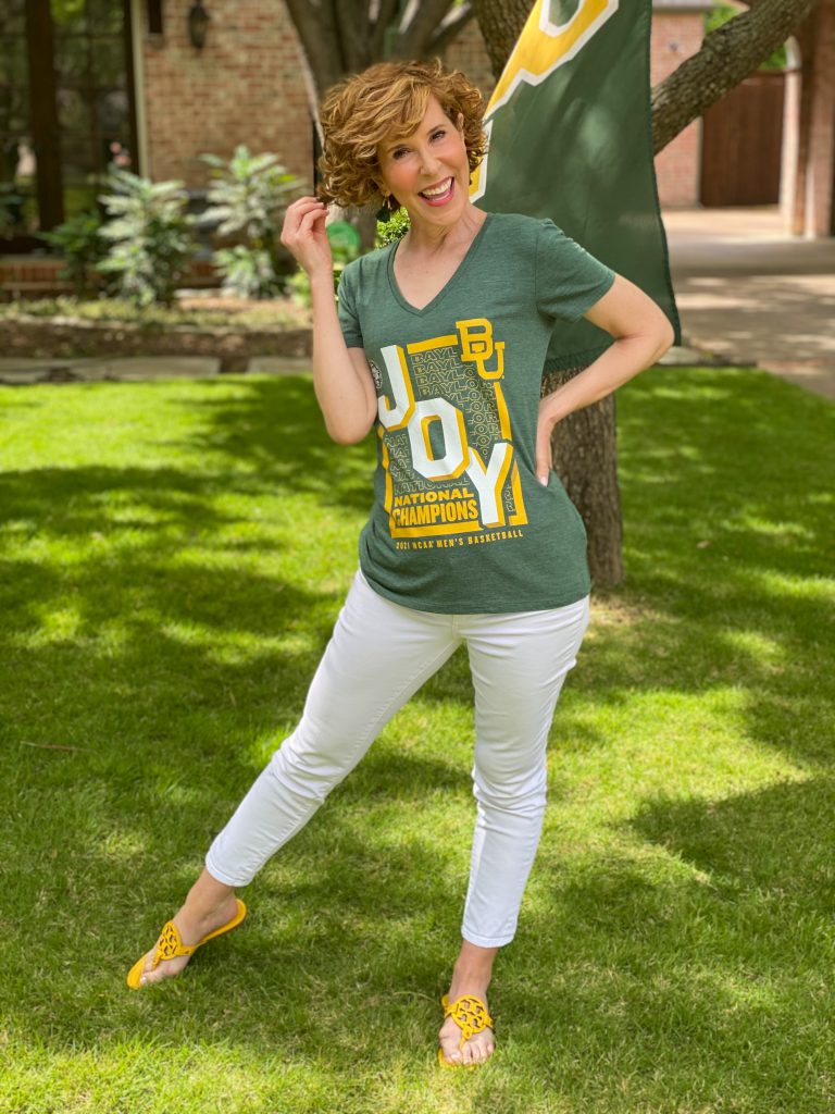 woman wearing green BU JOY tee and white jeans standng in a front yard