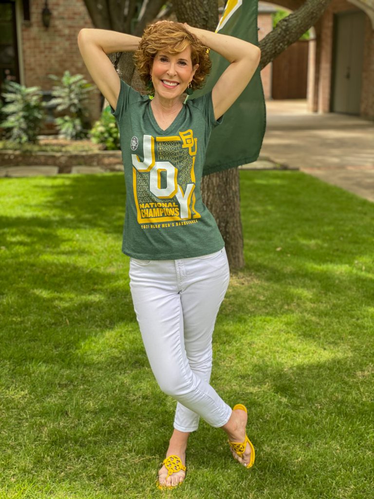 woman wearing green BU JOY tee and white jeans standng in a front yard