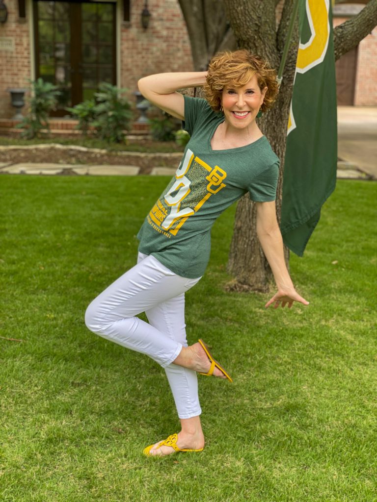 woman wearing green BU JOY tee and white jeans standng in a front yard