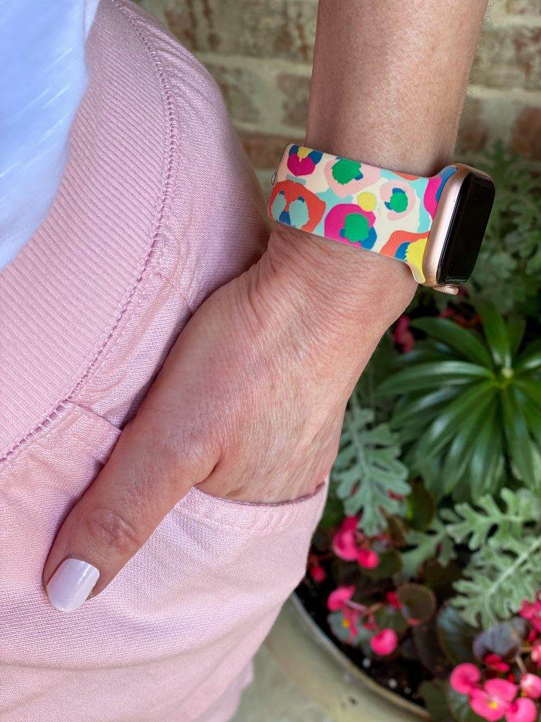 woman with hand in pocket of pink pants showing multicolored apple watch band