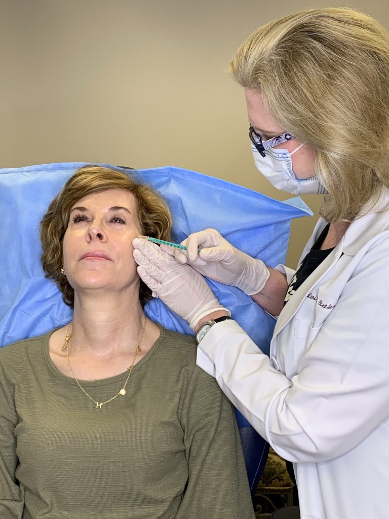 woman over 50 wearing green dress receiving botox injections from dr. lori stetler of dallas center for dermatology and aesthetics