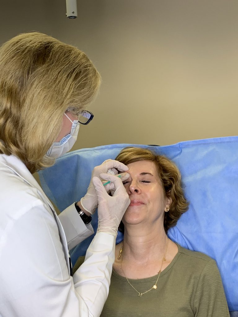 woman over 50 wearing green dress receiving botox injections from dr. lori stetler of dallas center for dermatology and aesthetics