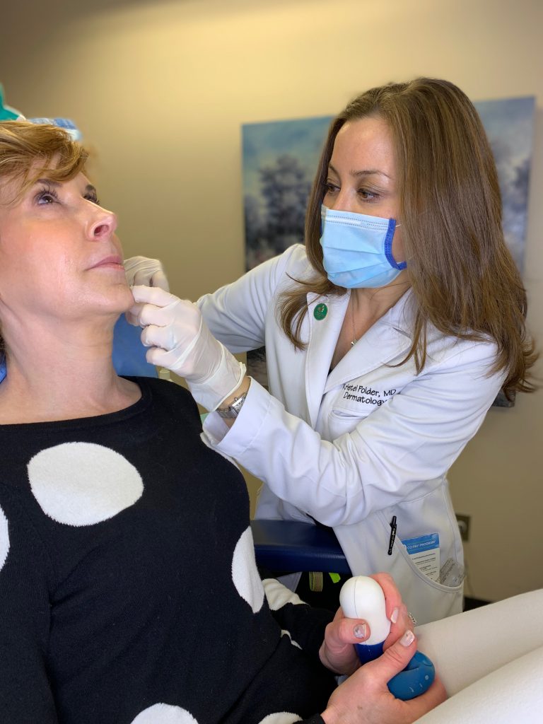 dr kristel polder from the dallas center for dermatology and aesthetics performing dermal fillers on a woman over 50 wearing black and white polka dot sweater