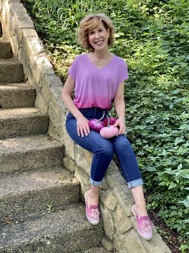 woman wearing WHBM ombre pink jetsetter tee, mott & bow jeans and WHBM espadrille mules and holding 3 pink velvet pumpkins