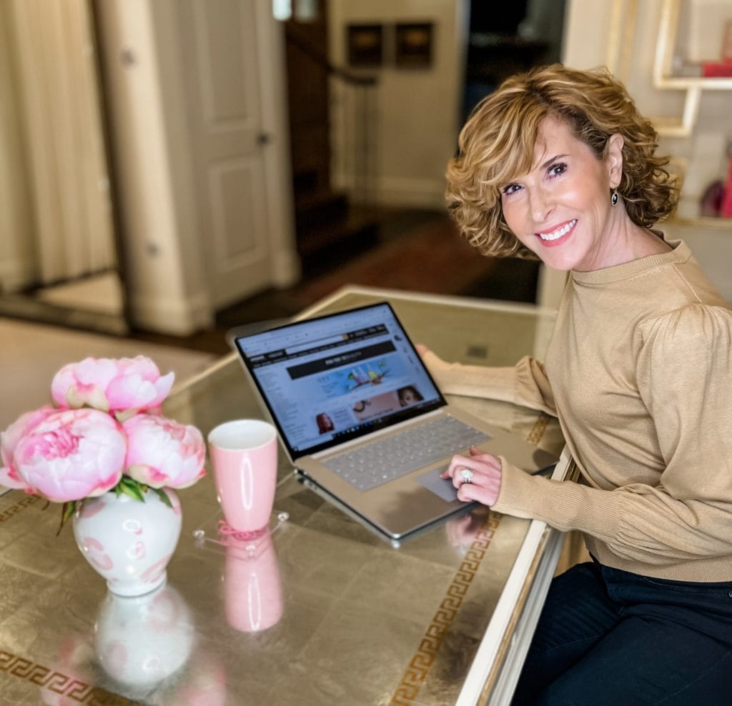 Woman sitting at desk looking at amazon premium beauty page on laptop