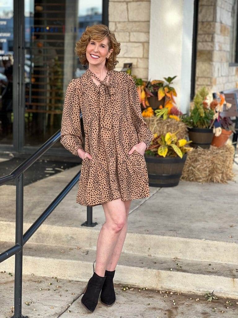 woman over 50 wearing nordstrom halogen Tie Neck Tiered Long Sleeve Dress and black suede booties standing in front of princi italia Italian restaurant