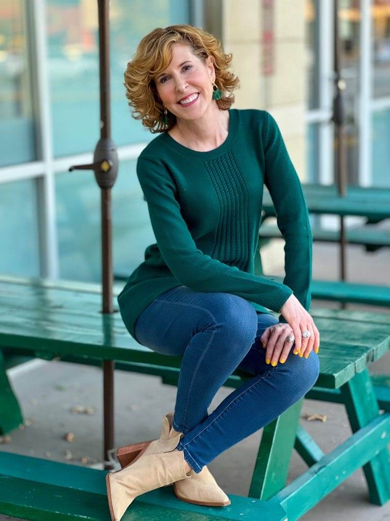 woman sitting on green picnic table wearing soft surroundings priscilla pullover tunic sweater and Supremely Soft Relaxed Straight Jeans