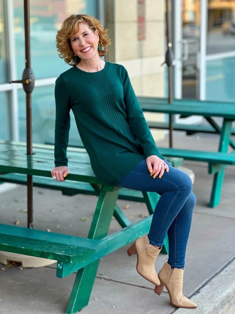 woman sitting on green picnic table wearing soft surroundings priscilla pullover tunic sweater and Supremely Soft Relaxed Straight Jeans