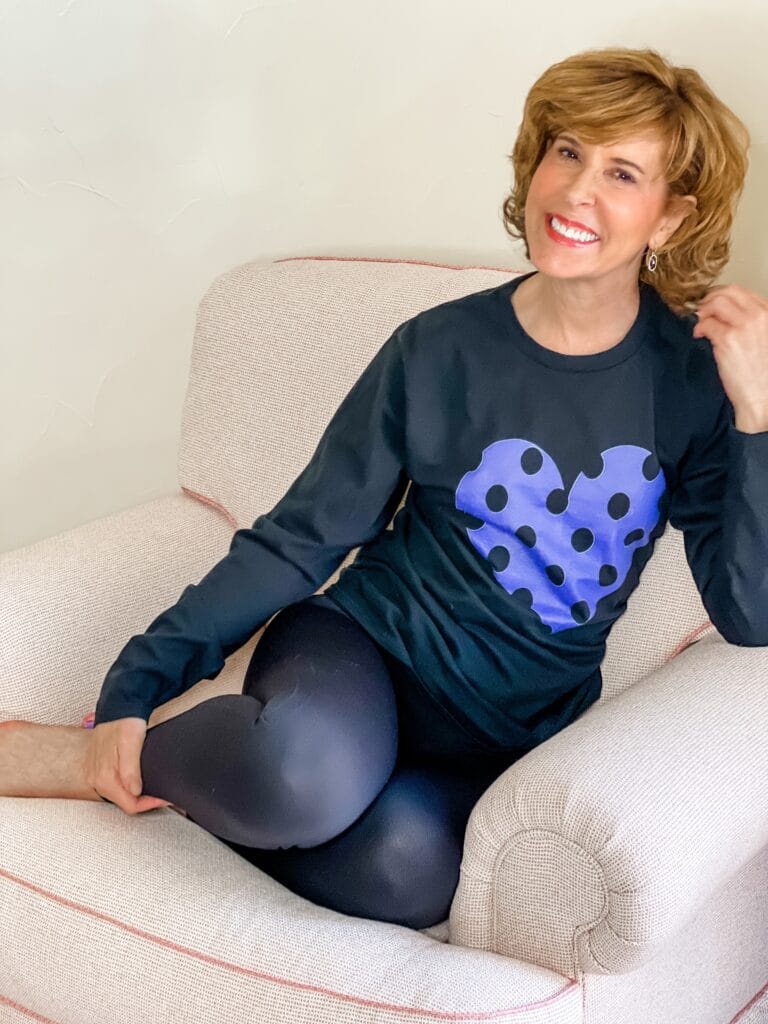 woman sitting in a chair wearing a black tee with a polka dot heart in very peri the pantone color of the year