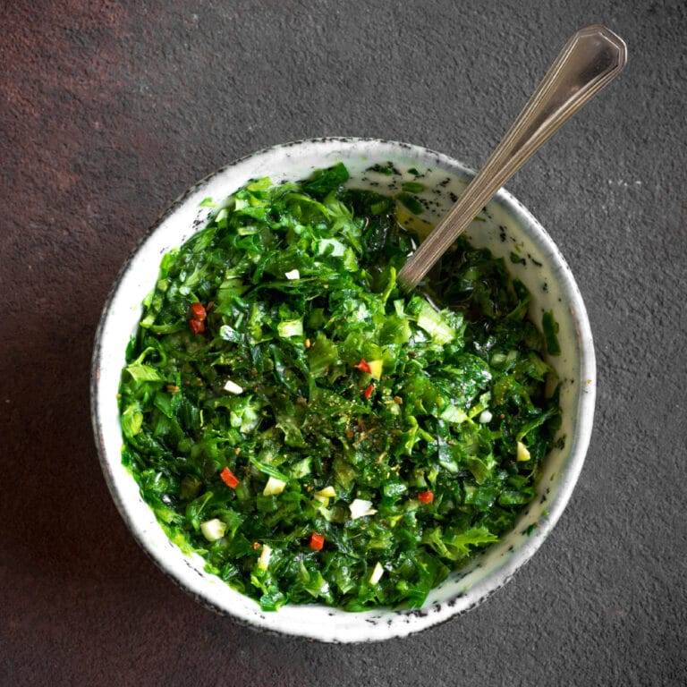 chimichurri sauce in white bowl on dark gray tabletop