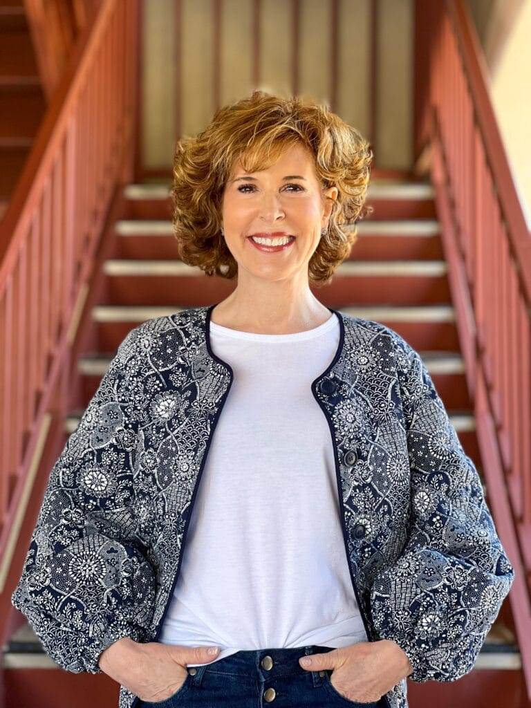 woman over 50 posing on staircase wearing Treasure & Bond Quilted Puff Sleeve Jacket by Nordstrom with a white tee - transition your wardrobe from winter to spring