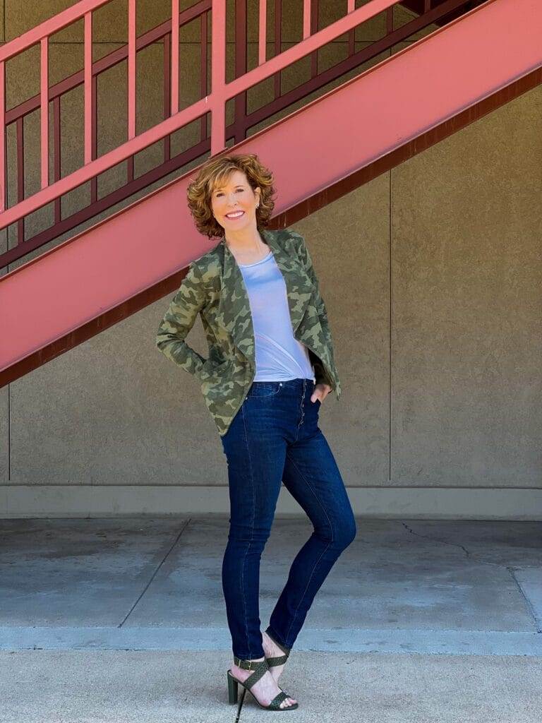 woman over 50 standing on the side of a staircase wearing Drape Collar Knit Blazer and button front jeans