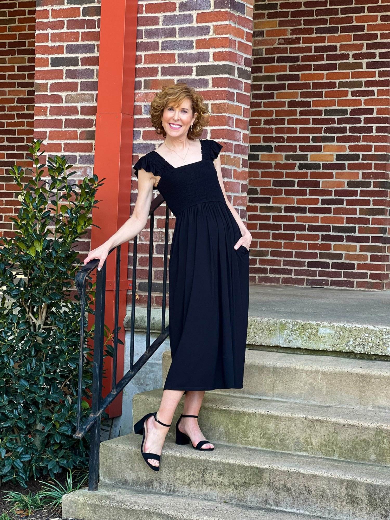 woman over 50 posing against a wrought iron stair rail outside on a staircase wearing Moonlight Dress from NORDSTROM