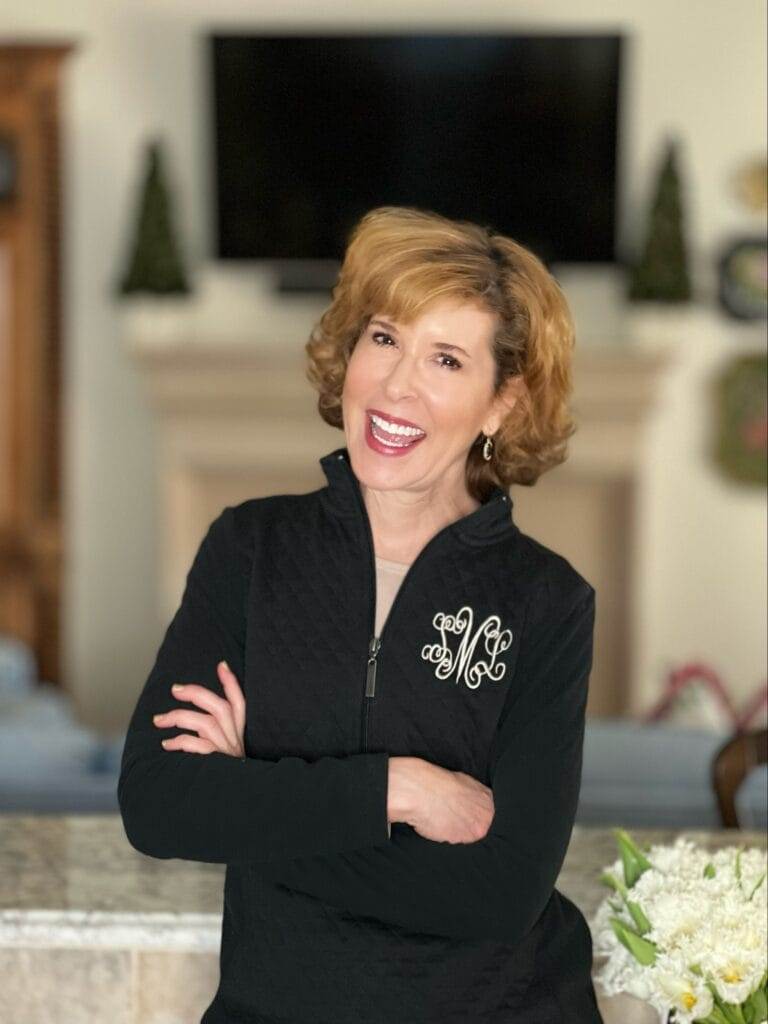 woman sitting in her home with her arms crossed wearing a black 1/4 zip quilted pullover sharing essential skills for college students