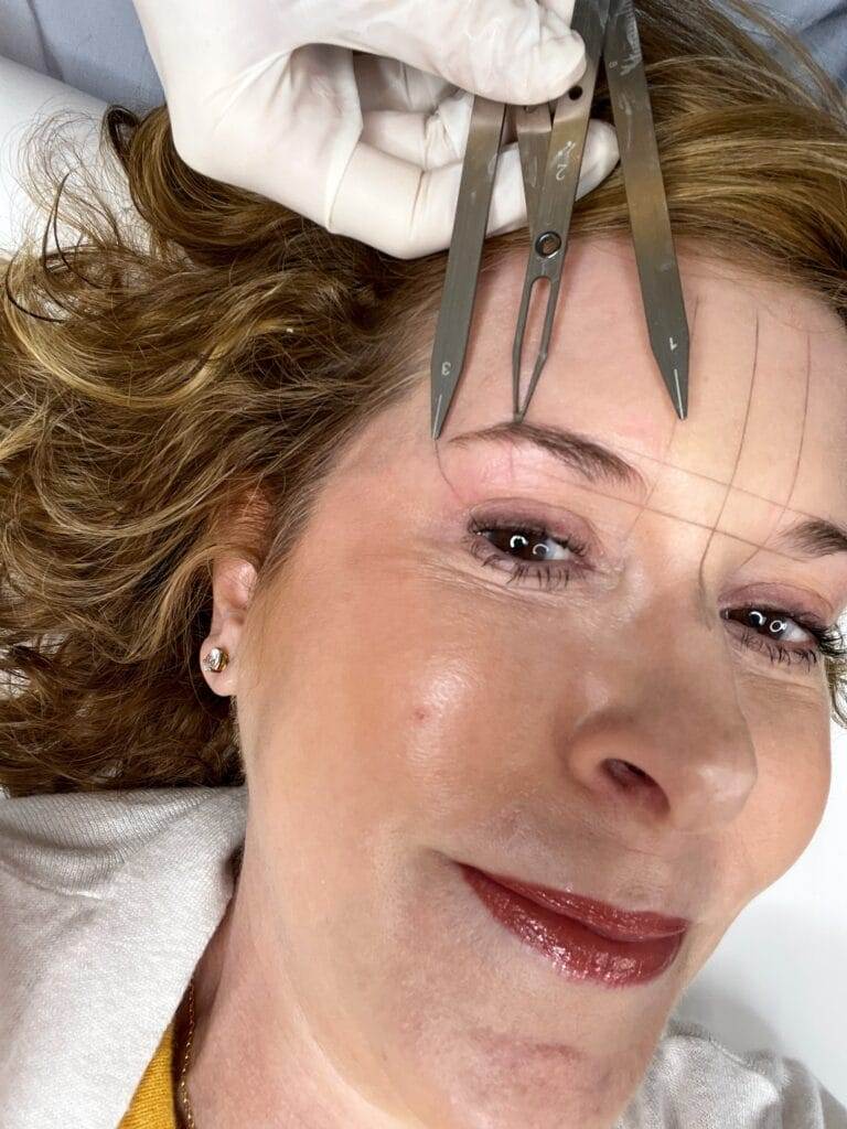 woman's face with caliper and brow markings prior to microblading