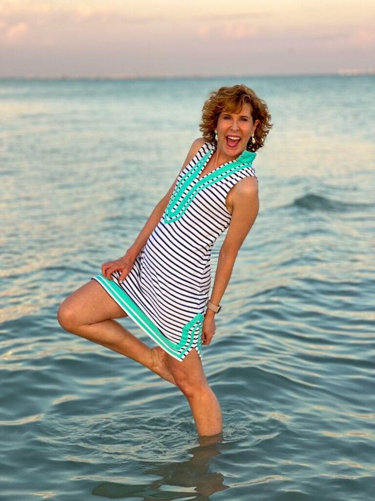 woman over 50 posing in the surf in a beach outfit