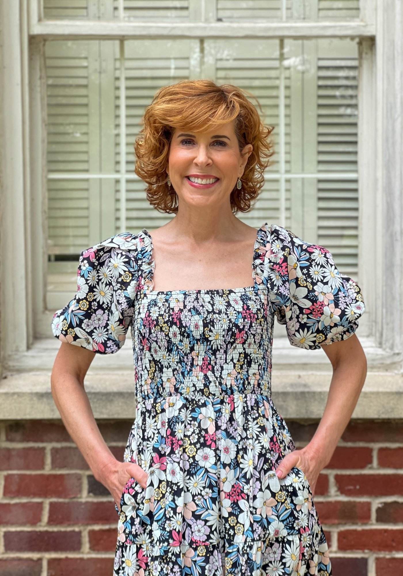 woman over 50 wearing Rachel Parcell Smocked Puff Sleeve Midi Dress from Nordstrom standing in front of a window wondering what to wear to a summer wedding