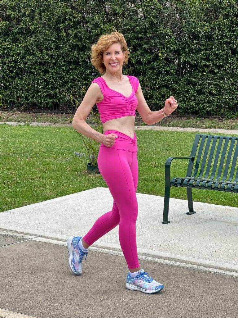 close up of woman over 50 walking for health on walking path weairing free people Movement Breathe Deeper Leggings and crop top by a bench