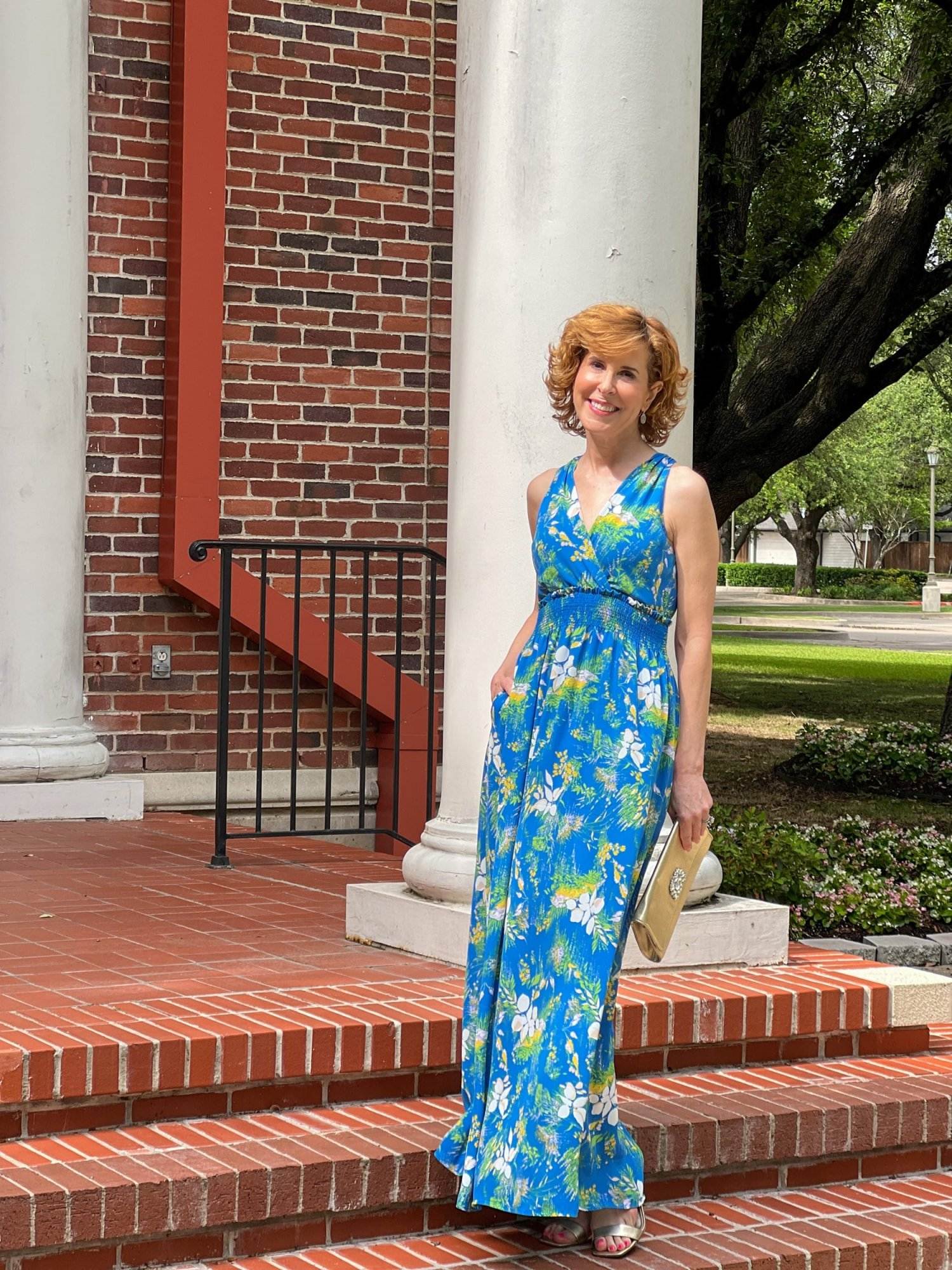 woman wearing blue maxi dress standing in front of a white column