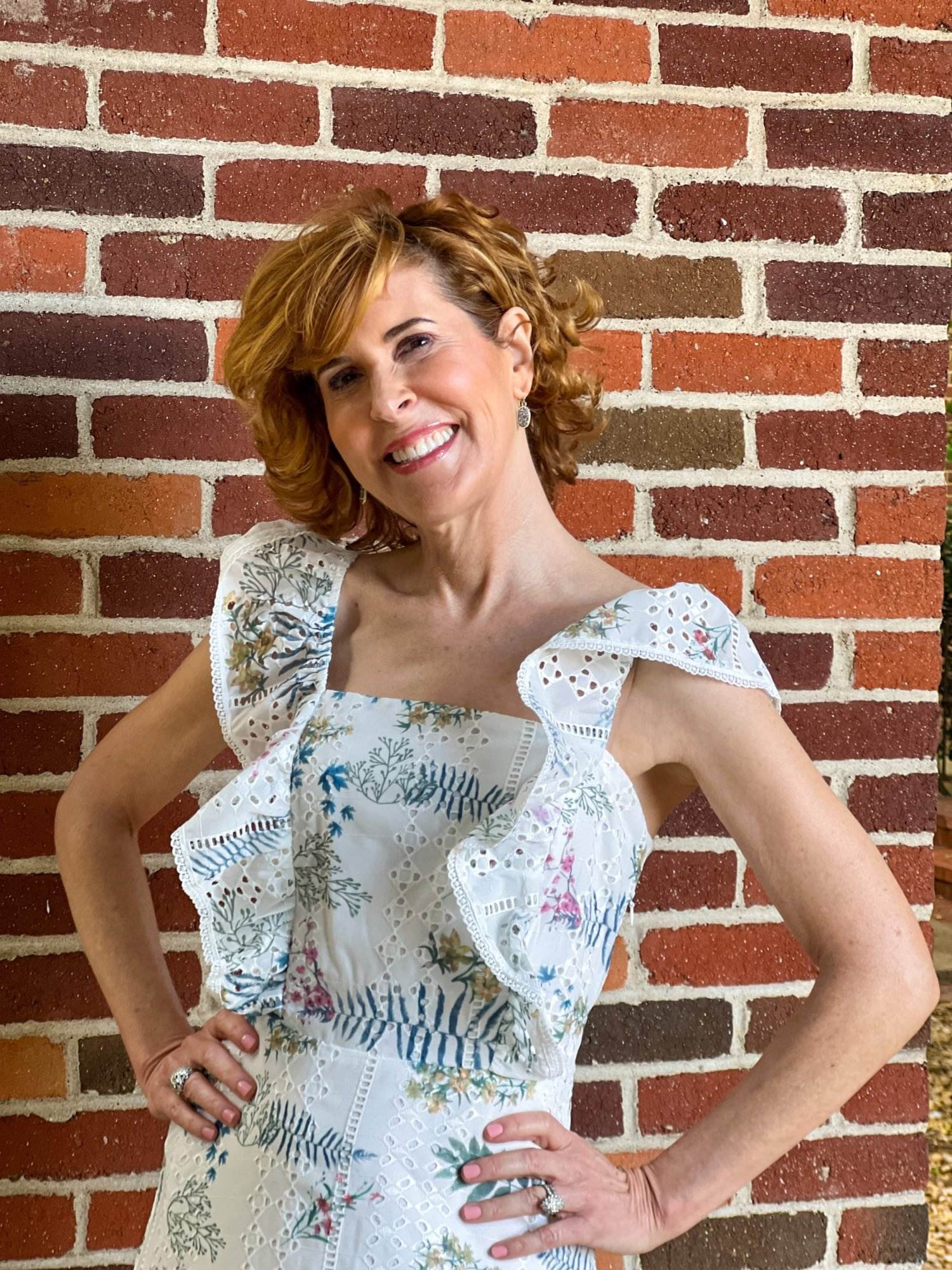 woman over 50 standing in front of a brick wall wearing Chelsea28 Eyelet Floral Ruffle Minidress